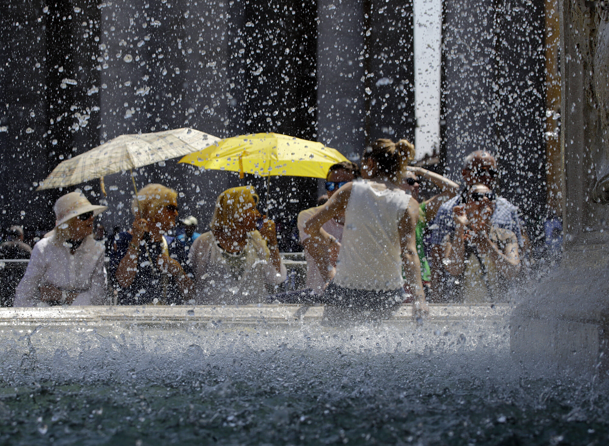 CORRECTS SPELLING IN THE SLUG - Tourists and faithful cool off near the Lorenzo Bernini's fountain as they wait for the start of Pope Francis Angelus prayer in St. Peter's Square, at the Vatican, Sunday, June 7, 2015. (AP Photo/Gregorio Borgia)